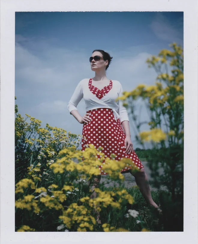 Vrouw in witte top en rode polkadot rok in een bloemenveld