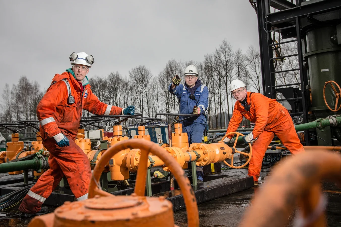 Team van medewerkers in oranje pakken bij gaskranen