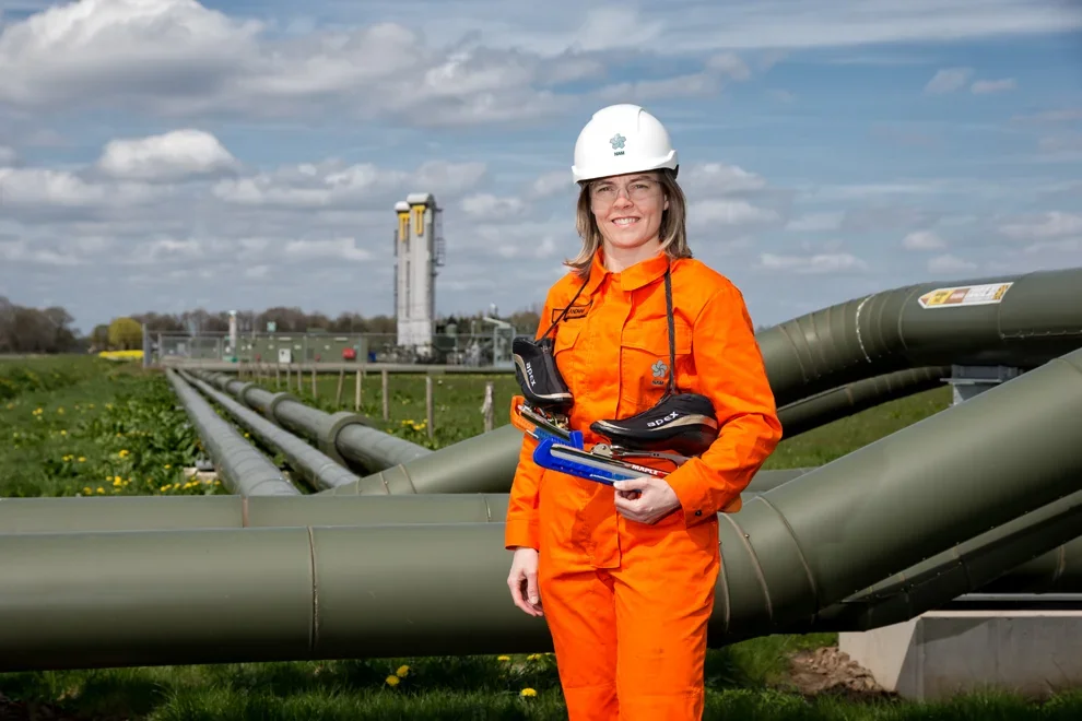 Ingenieur in oranje pak met tablet bij een pijpleidinginstallatie