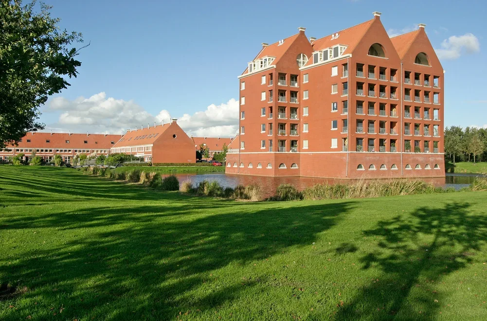 Groot rood bakstenen gebouwencomplex met groen grasveld