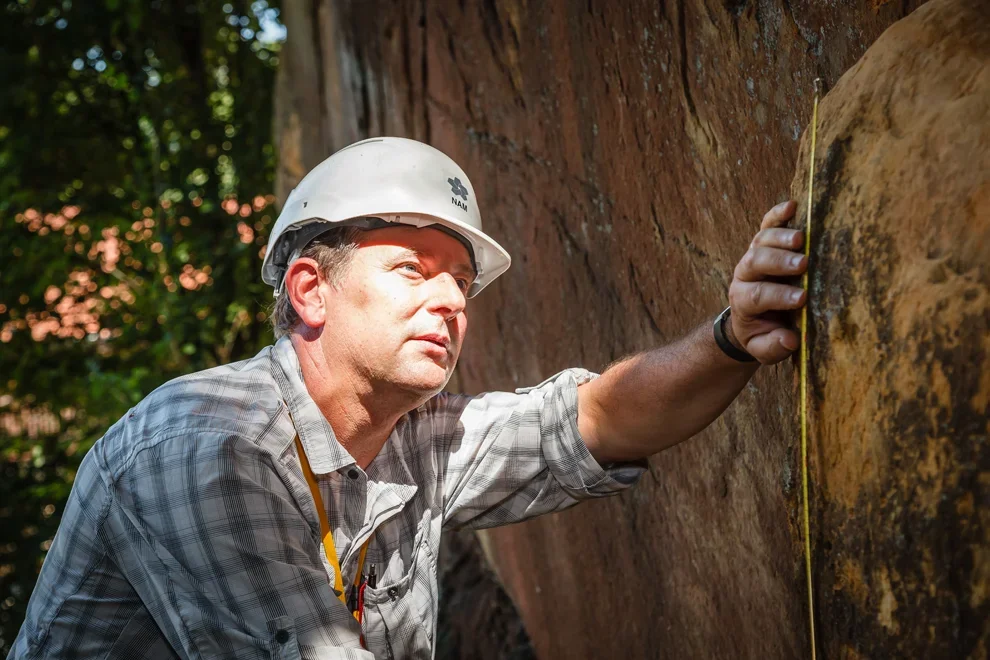 Medewerker met helm inspecteert een grote houten constructie