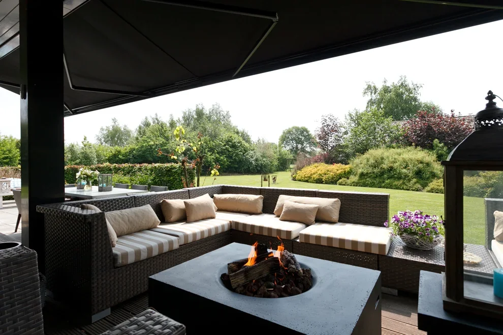 Buitenlounge met tuinbank en vuurschaal onder pergola