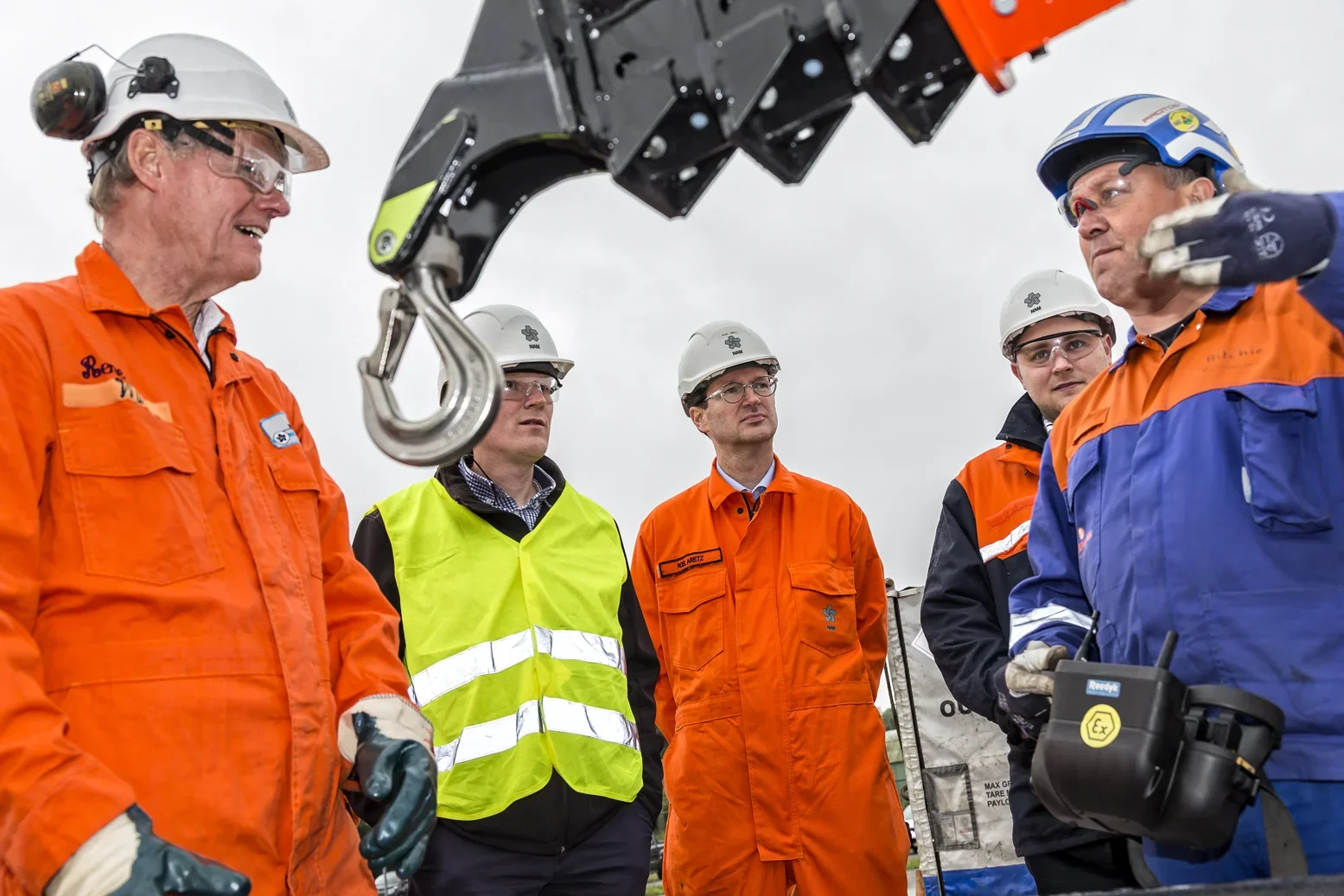 Team van medewerkers in oranje pakken en helmen op een industriële locatie