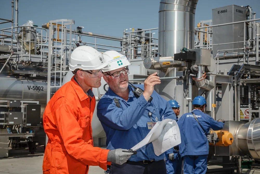 Twee ingenieurs bespreken plannen bij een gasverwerkingsinstallatie