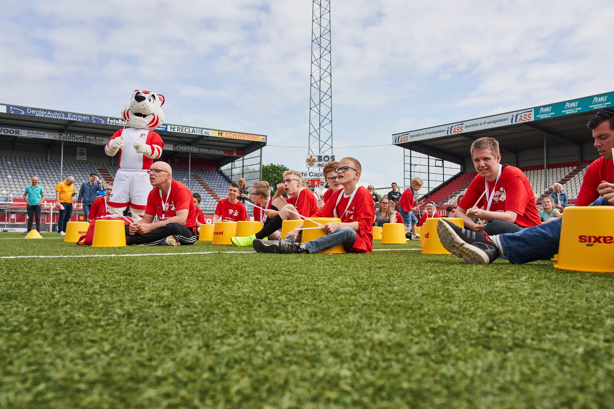 Kinderen poseren met een voetbalclubmascotte op een stadionveld
