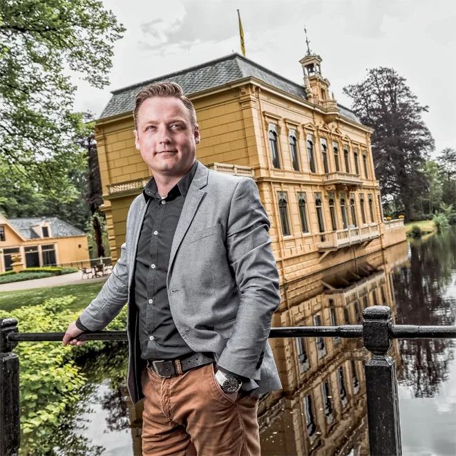 Man in casual jas voor een statig landhuis
