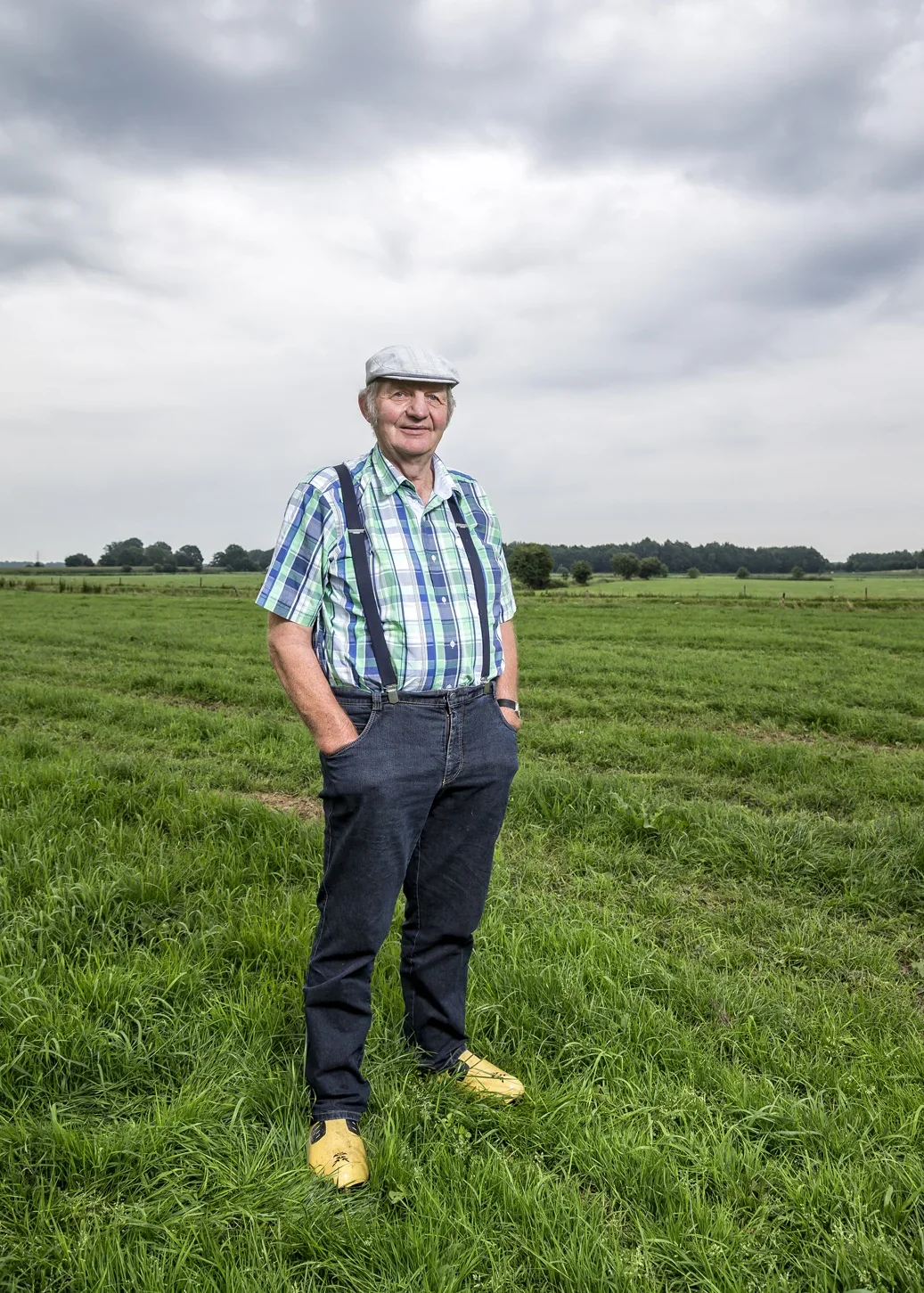 Man staat in een groen veld onder een bewolkte hemel