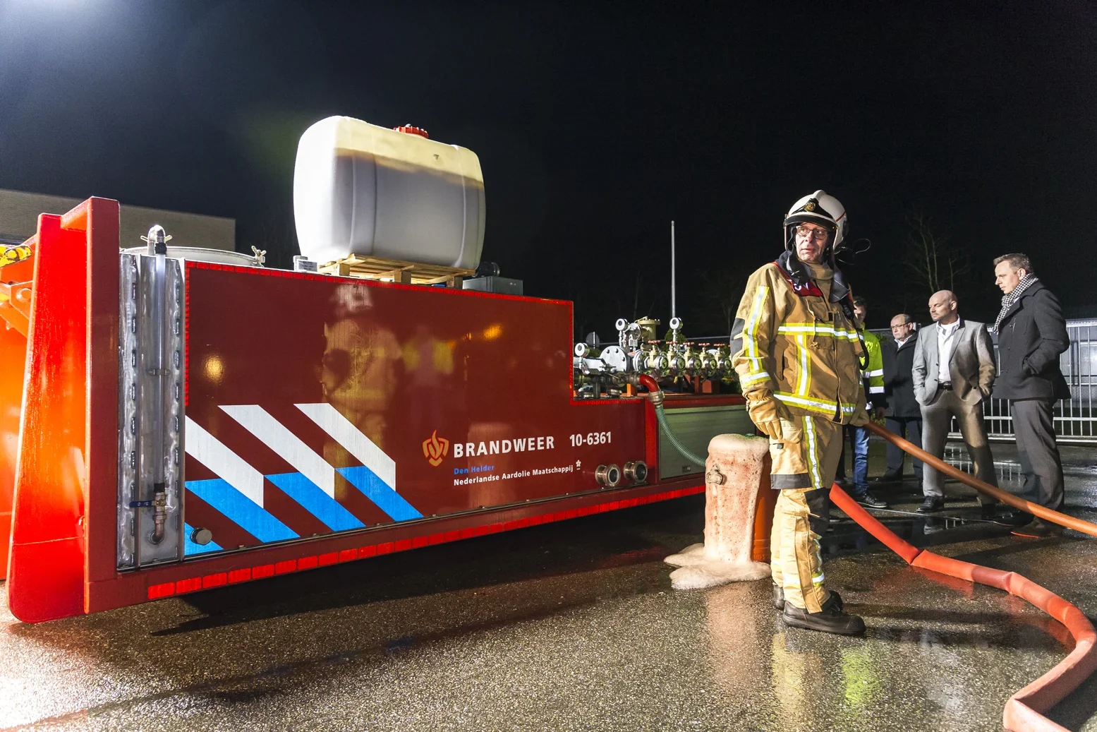 Brandweerman in vol tenue naast een brandweerwagen 's nachts