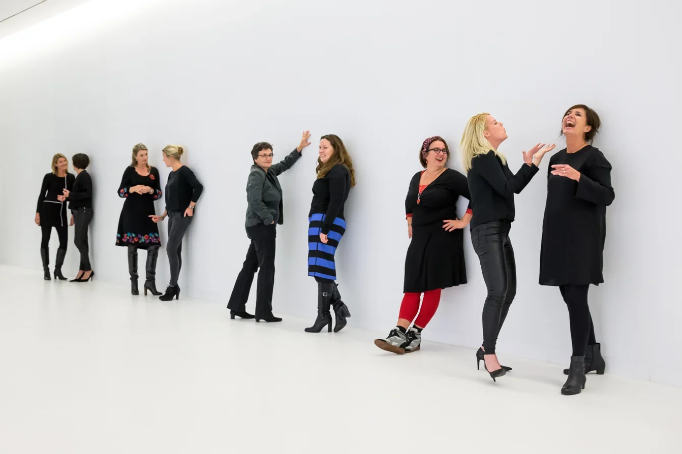 Groepsportret van vrouwen in kleurrijke outfits op een witte studioachtergrond