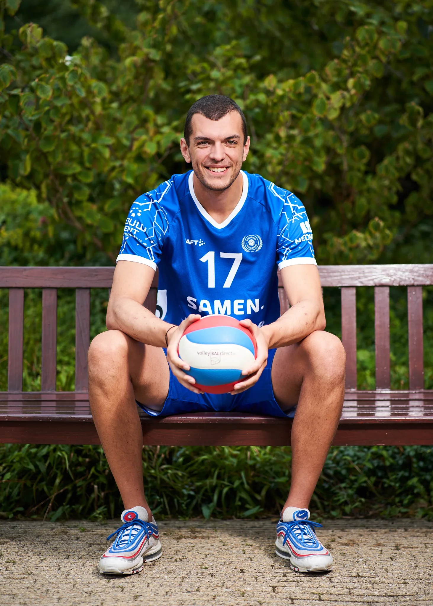Volleybalspeler in blauw teamtenue nummer 17 zit op een bank