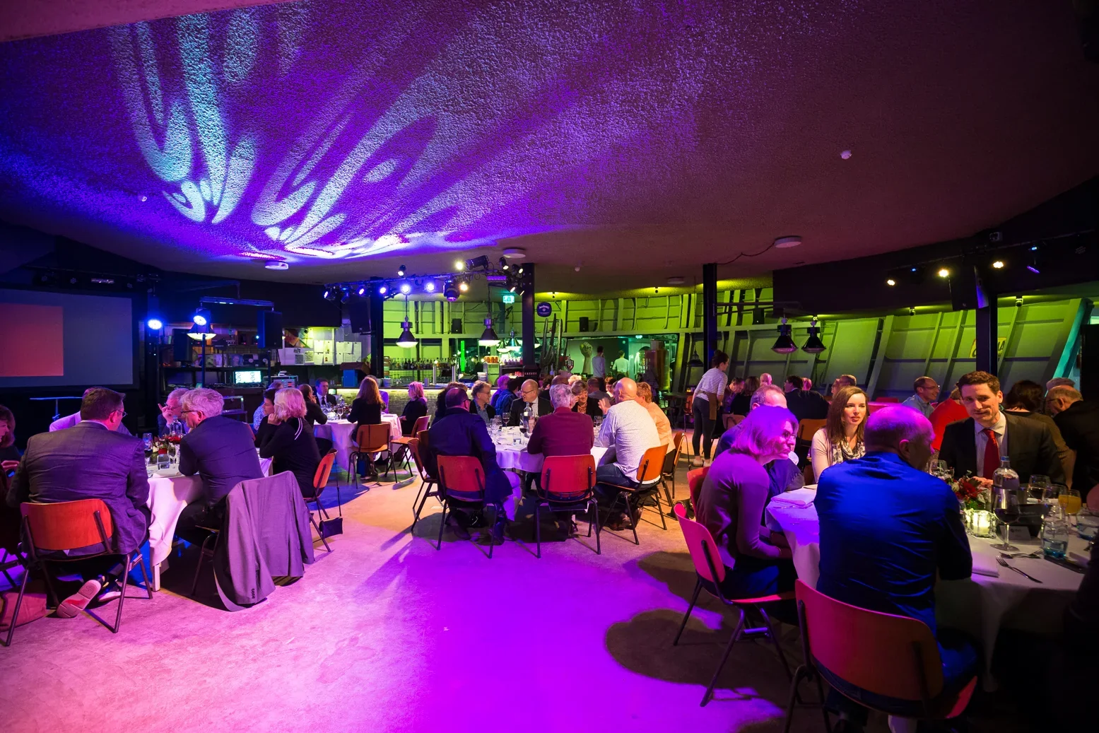 Avondevenement met paarse podiumverlichting en zittend publiek